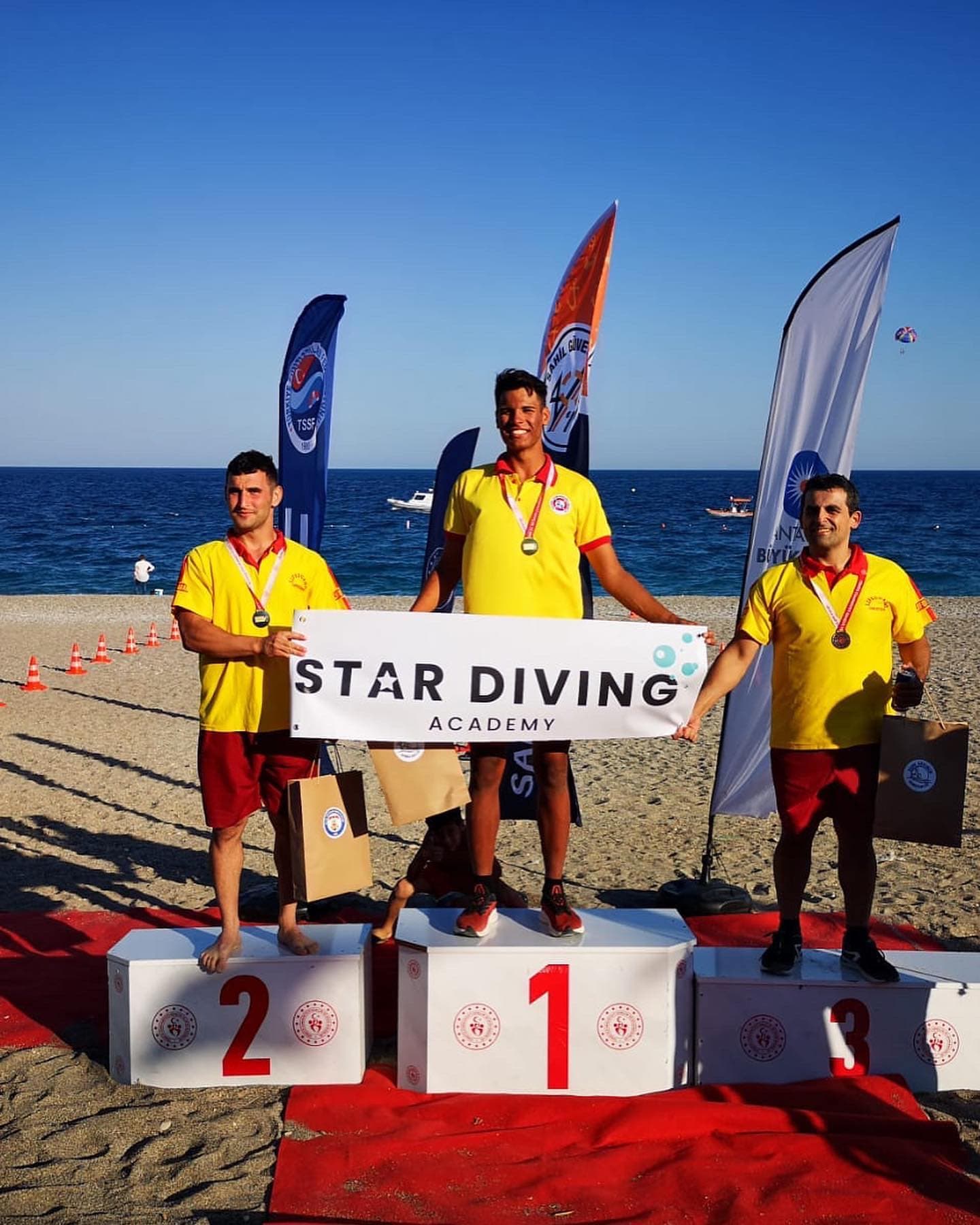 Cankurtarma şampiyonasında madalya kazanan sporcular sahildeki podyumda